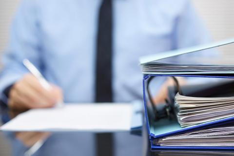 Homme derrière un bureau avec des dossiers.